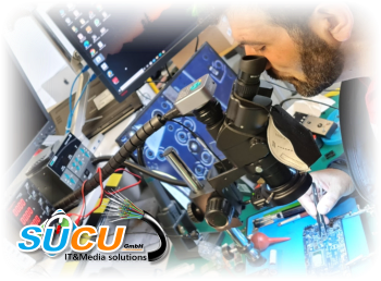 Özcan SUCU am Elektronik-Arbeitsplatz mit Stereomikroskop bei einer Platinenreparatur
